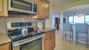 Una cocina con electrodomésticos de acero inoxidable, armarios de madera y encimera de granito.