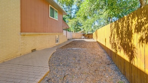 A residential backyard with a paved walkway, a wooden fence, and a house with a window. - 9 Mi to Dtwn Denver: Aurora Vacation Rental (Aurora)