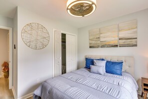 A bedroom with a large bed, a circular wall decoration, and a ceiling light fixture. - Greensboro Vacation Rental w/ Patio, Yard! (Greensboro)
