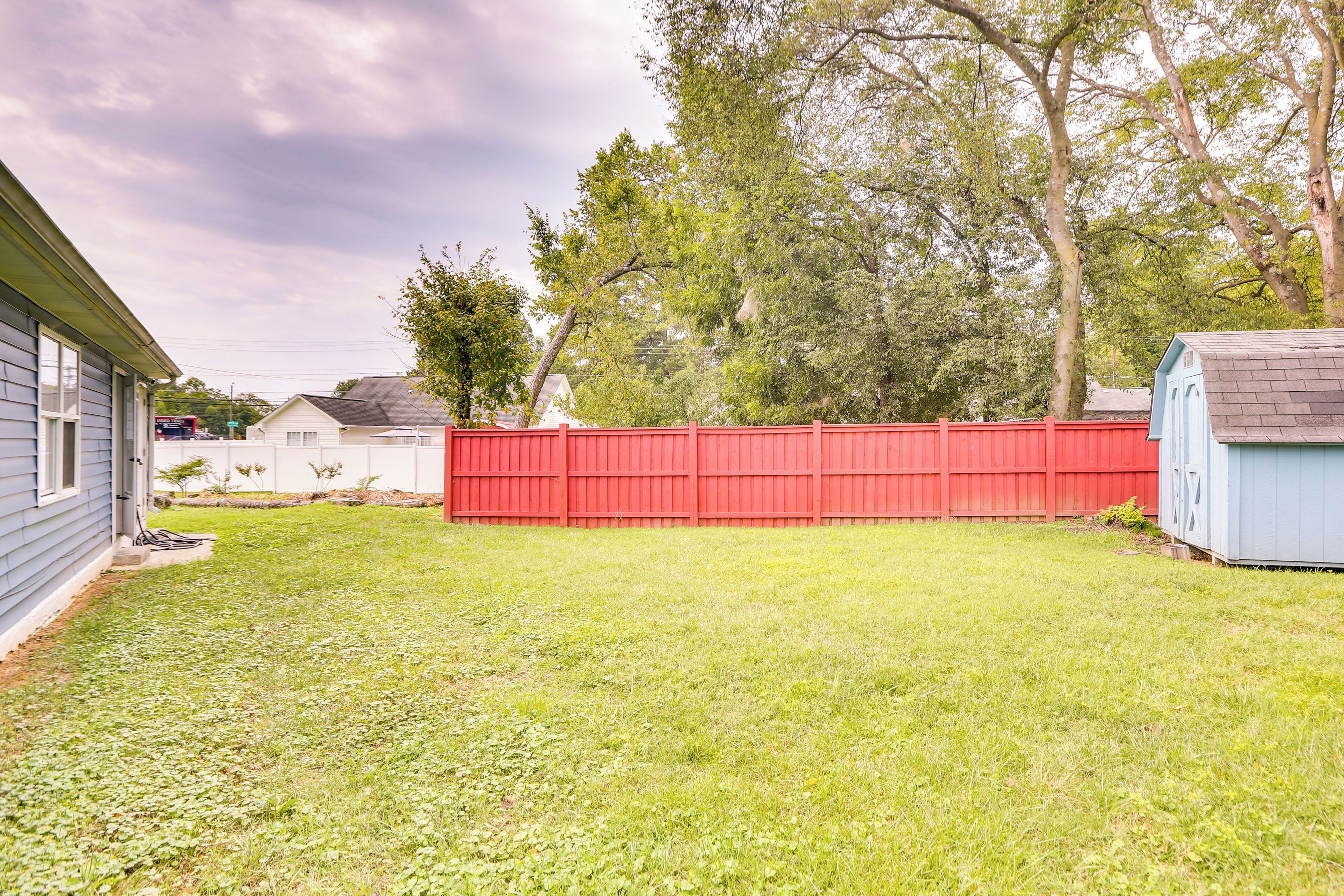 A backyard with a red fence, a shed, and a house.