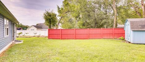 A backyard with a red fence, a shed, and a house.