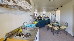 Een compacte keuken met een spoelbak, fornuis en een eethoek met stoelen en een tafel.