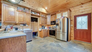 A spacious kitchen with wooden cabinets, a stone floor, and stainless steel appliances. - Fort Towson Cabin < 1 Block to Raymond Gary Lake (Fort Towson)