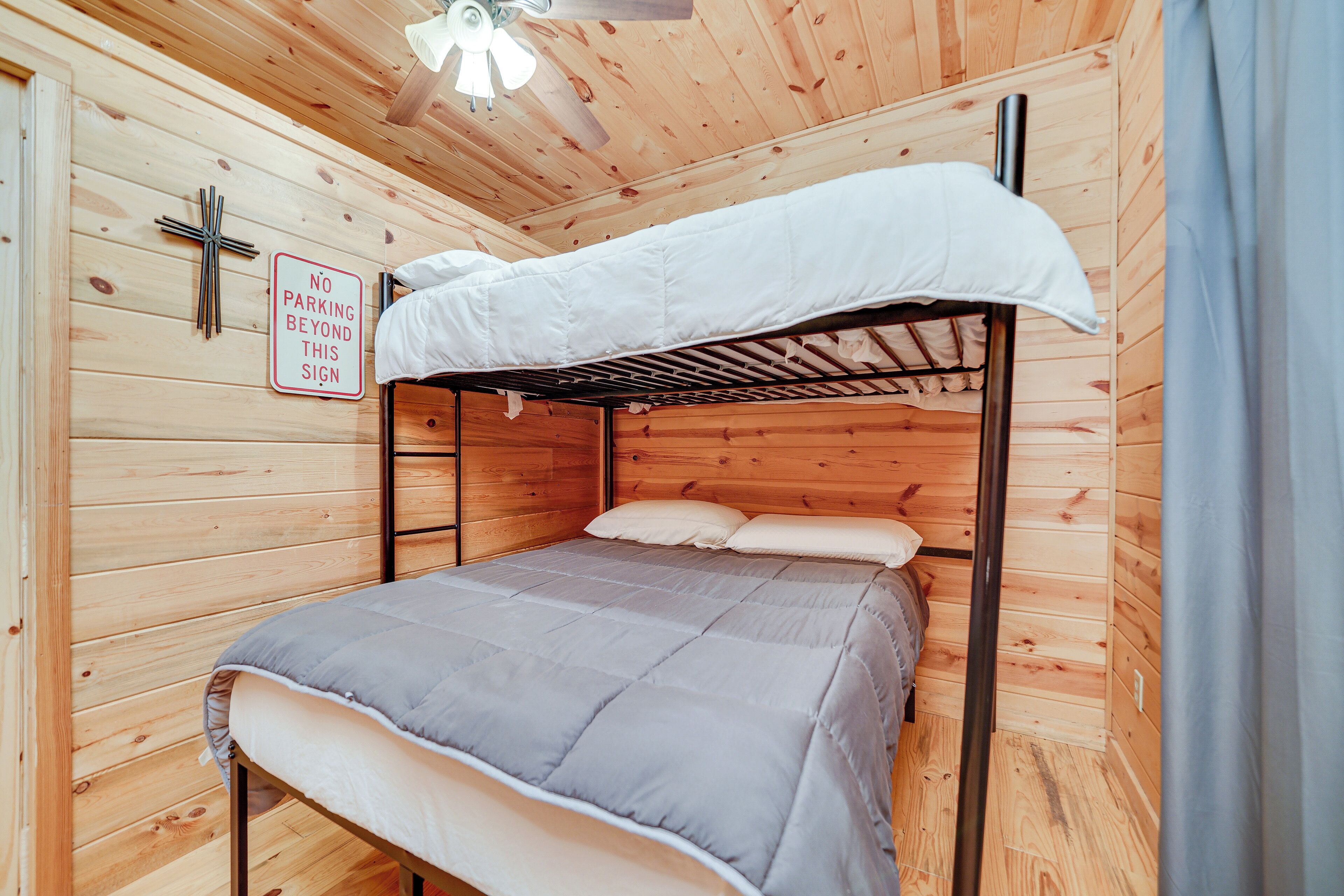 A bunk bed in a wooden cabin room with a 'No Parking Beyond This Sign' on the wall.