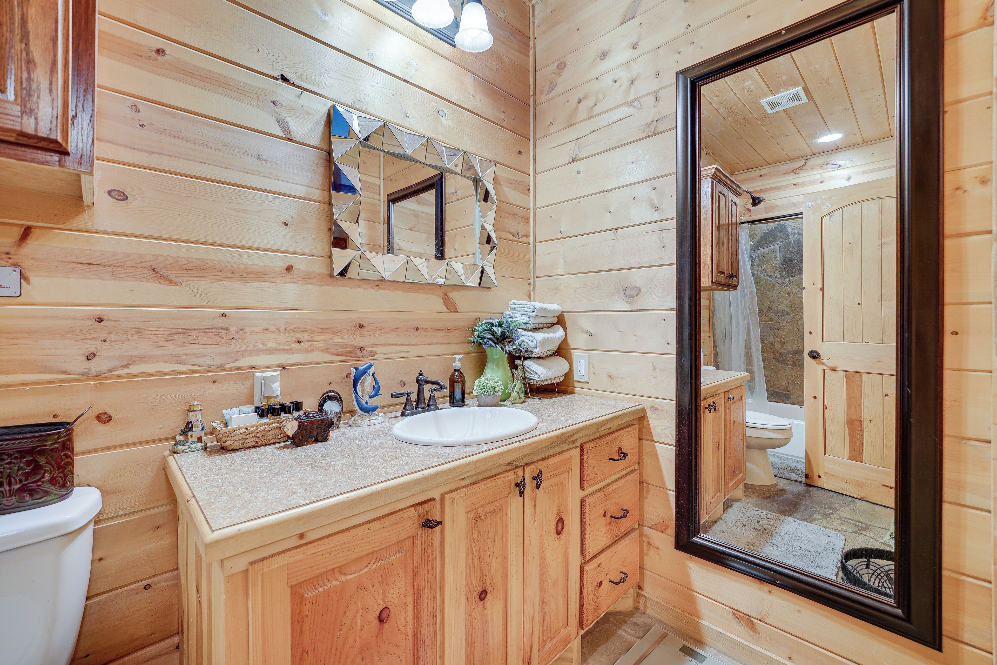 A wooden cabin bathroom with a sink, mirror, and wooden cabinets.