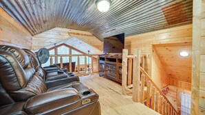 A wooden cabin interior with a leather sofa, a fan, and a fireplace. - Fort Towson Cabin < 1 Block to Raymond Gary Lake (Fort Towson)