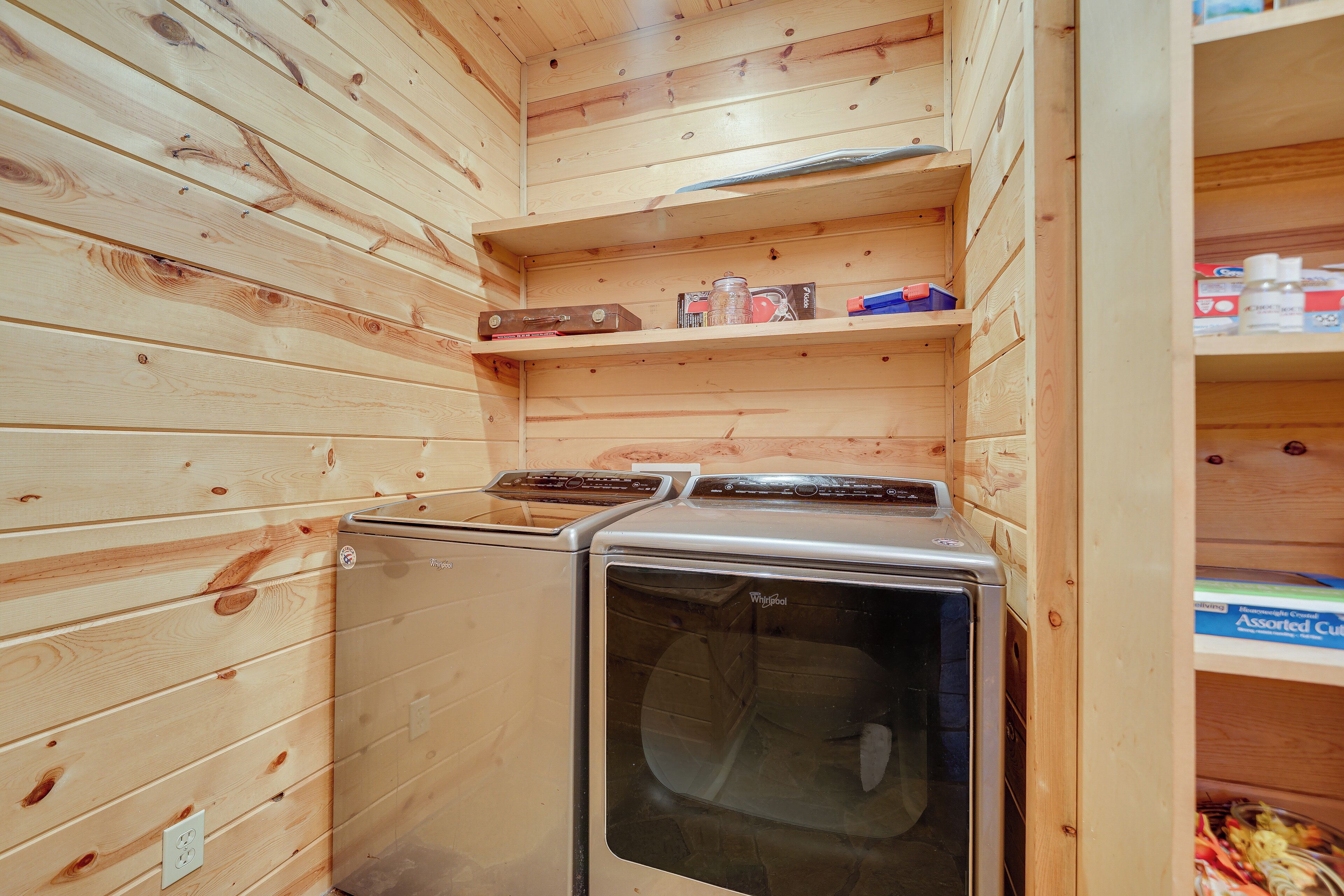 Una lavanderia piccola con pareti e mensole di legno, contenenti articoli per la pulizia.