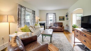 A living room with a sofa, a coffee table, a TV, and a fireplace. - Family-friendly Jackson Home w/ Sunroom: Near Golf (Jackson)
