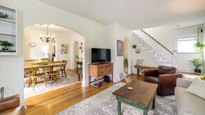 A spacious living room with a wooden dining table, a leather sofa, and a staircase leading to an upper floor. - Family-friendly Jackson Home w/ Sunroom: Near Golf (Jackson)