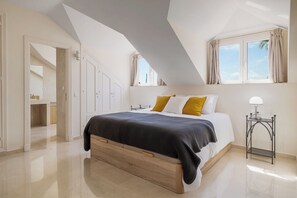Quarto com cama, mesa de cabeceira e janela com cortinas.
