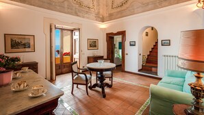 A dining area with a round table, chairs, and a coffee station. There is a staircase leading to an upper floor. - Casa Marina (Positano)