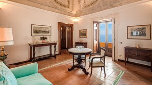A spacious room with a round table, chairs, a sofa, and a balcony with a view. - Casa Marina (Positano)