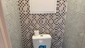 Un bagno piccolo con un gabinetto, un cestino e un pensile sopra il water.
