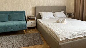 Una camera d'albergo ben ordinata con un letto, una poltrona, un comodino e un globo sul comodino.