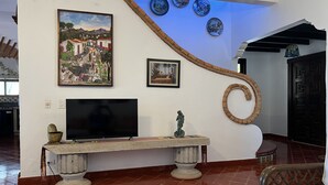 Un salon avec un téléviseur, un banc et des œuvres d’art accrochées au mur.