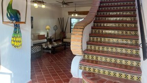 Un escalier orné de carreaux rouges et noirs, une décoration représentant un paon et un ventilateur de plafond.
