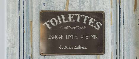 A sign with the word 'TOILETTES' and a usage limit of 5 minutes.