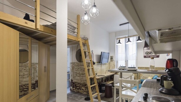 A compact kitchen with a wooden table, a ladder, and a TV. - St Léon Strasbourg - Studio - 3 Pers (STRASBOURG)
