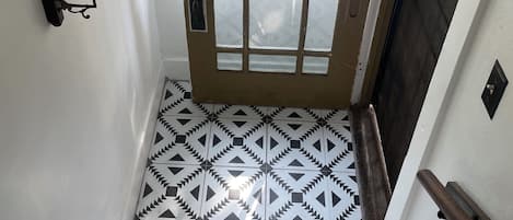 A staircase with a patterned floor leading to a door with a window.
