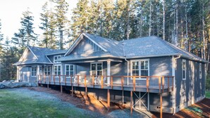 A two-story house with a deck, surrounded by trees. - Brand New October 2023! Ultimate Golfers House in Bandon! Adjacent Sheep Ranch! (Bandon)