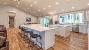 A spacious kitchen with a large island, white cabinetry, and a modern chandelier. - Brand New October 2023! Ultimate Golfers House in Bandon! Adjacent Sheep Ranch! (Bandon)