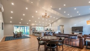 A spacious living area with a round dining table, leather sofa, and a large flat-screen TV. - Brand New October 2023! Ultimate Golfers House in Bandon! Adjacent Sheep Ranch! (Bandon)