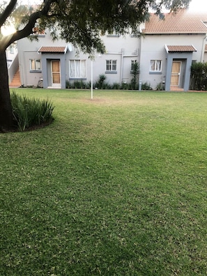 A residential property with a well-maintained lawn, a tree, and a house with a tiled roof and multiple windows. - Inviting 3-bed Apartment in Edenvale (Edenvale)