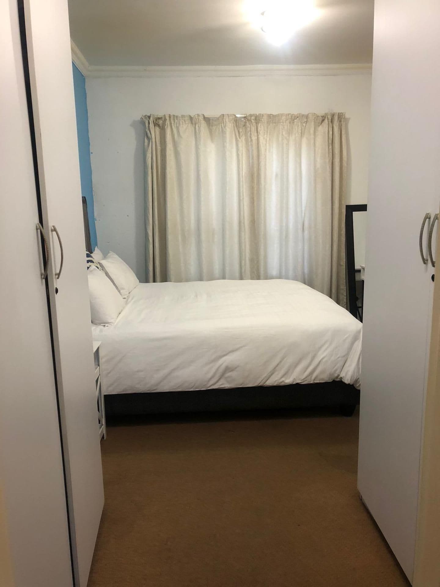 A bedroom with a bed, curtains, and a door.