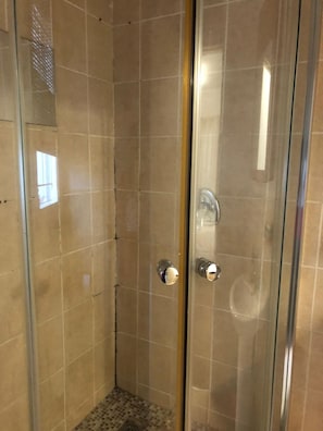A glass-enclosed shower stall with tiled walls and a floor, featuring a single showerhead and a door with a handle. - Inviting 3-bed Apartment in Edenvale (Edenvale)