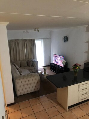 A living room with a sofa, a television, and a kitchen area with a countertop.