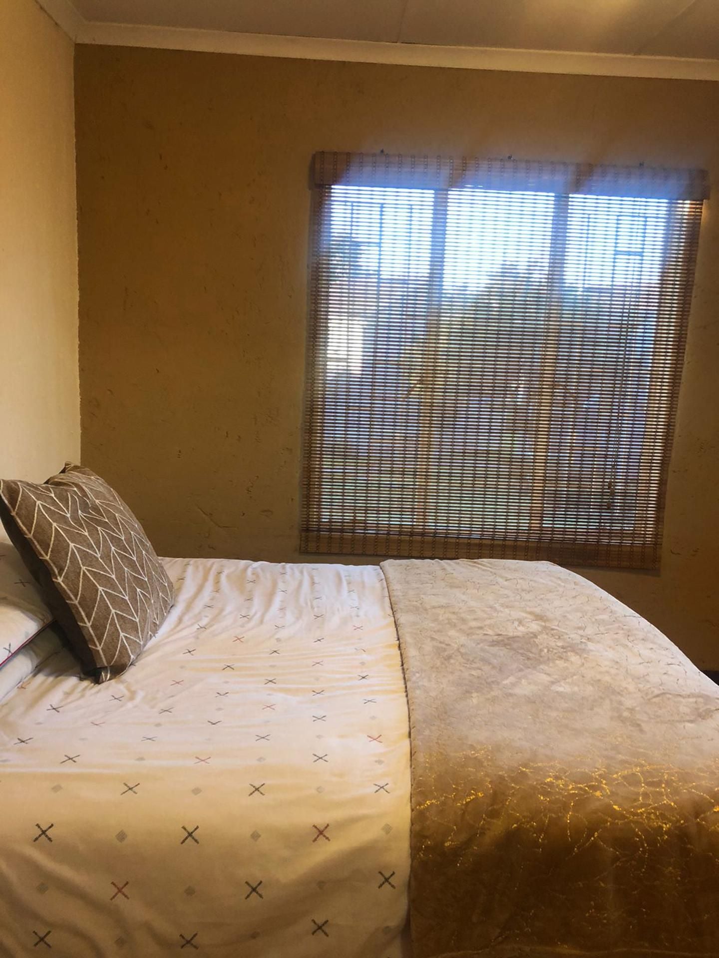 A room with a bed, a window with blinds, and a wall.