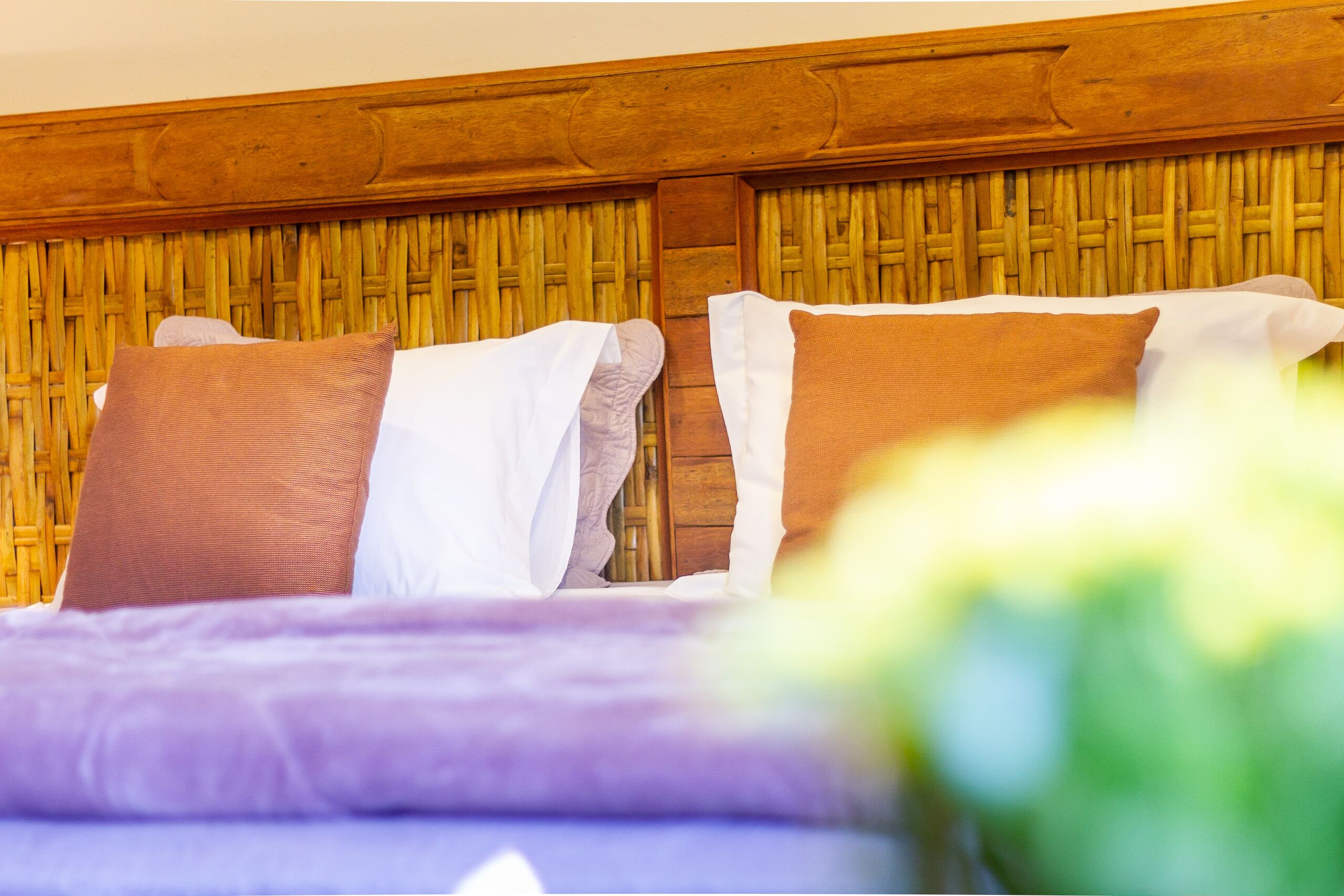 Una cama con cabecera de madera y dos almohadas, una marrón y otra blanca.