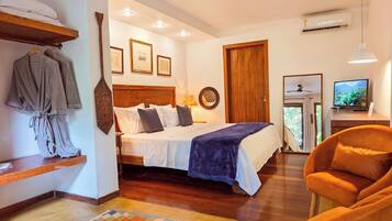 Quarto com cama, guarda-roupa, cadeira, televisão e porta.