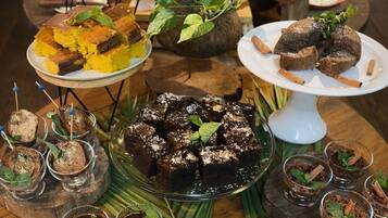 A round wooden table with various desserts and a potted plant.