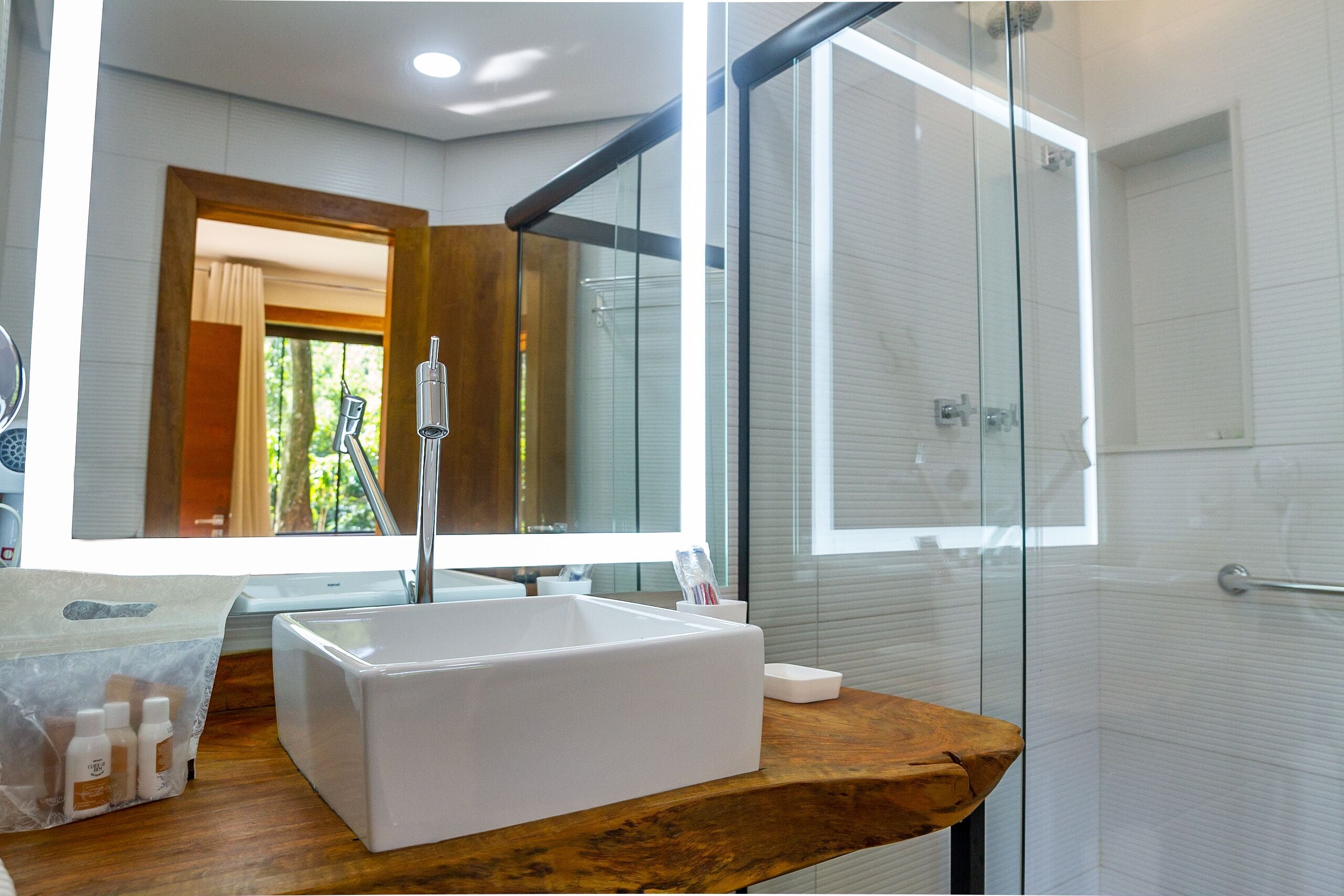 Un baño moderno con cabina de ducha de vidrio, tocador de madera y un espejo grande.