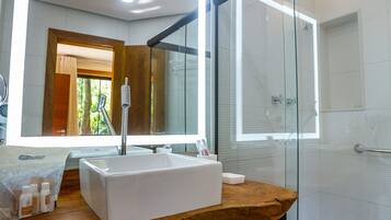 Un baño moderno con cabina de ducha de vidrio, tocador de madera y un espejo grande.