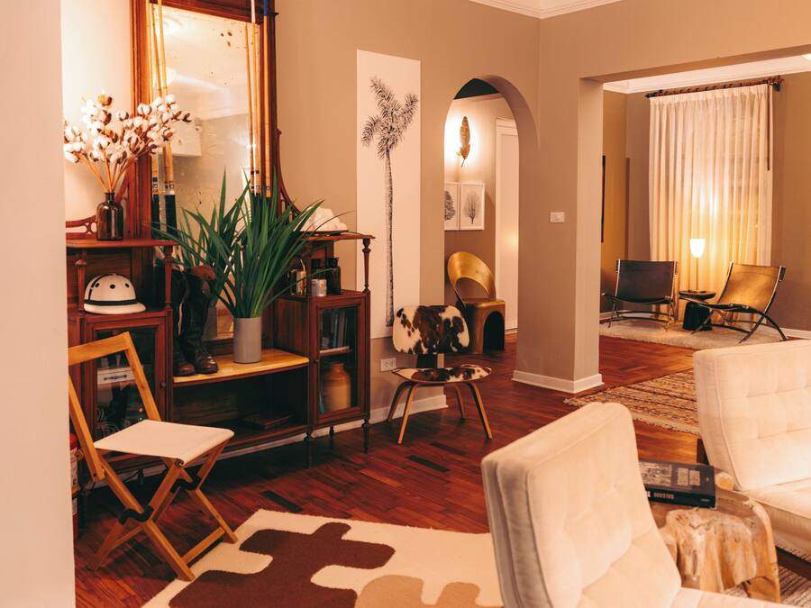 Un salon comprenant un canapé, des fauteuils, une table basse, une plante, une bibliothèque et un miroir.