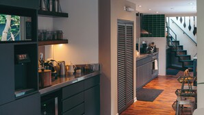Una cocina moderna con armarios oscuros, suelo de madera e iluminación colgante.