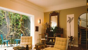 Una sala de estar con un sofá, sillas, una mesa de centro, una estantería y una escalera.