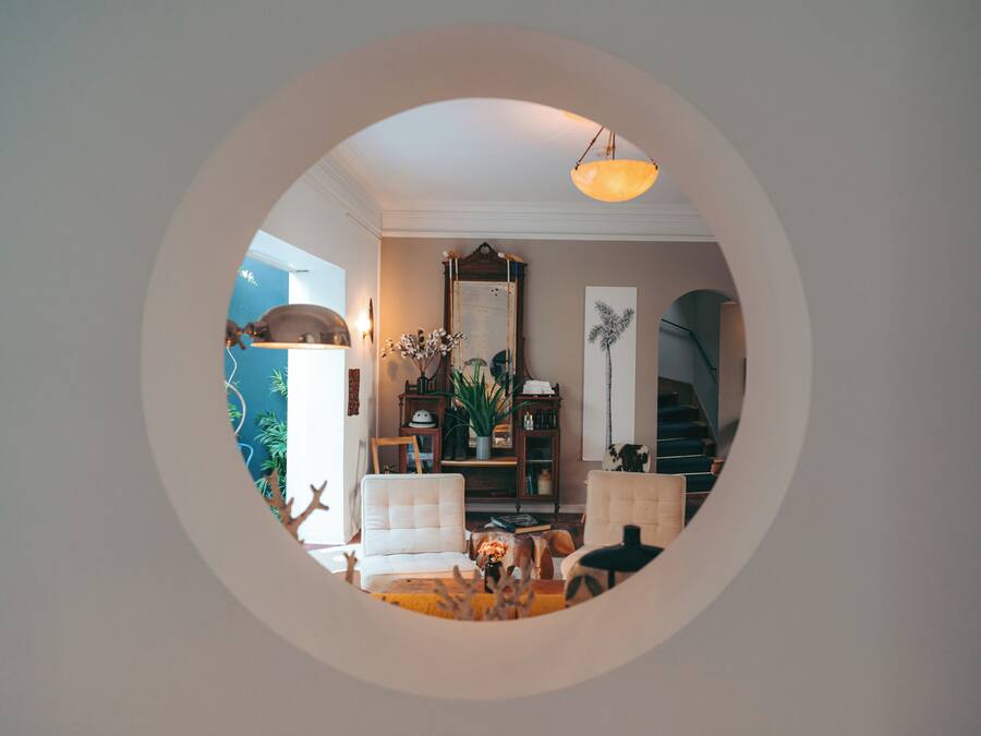 Vista circular de una sala de estar con sofá, lámpara, estantería y escalera.