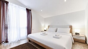 Ein Hotelzimmer mit einem großen Bett, zwei Nachttischen, einem Fenster mit Vorhängen.