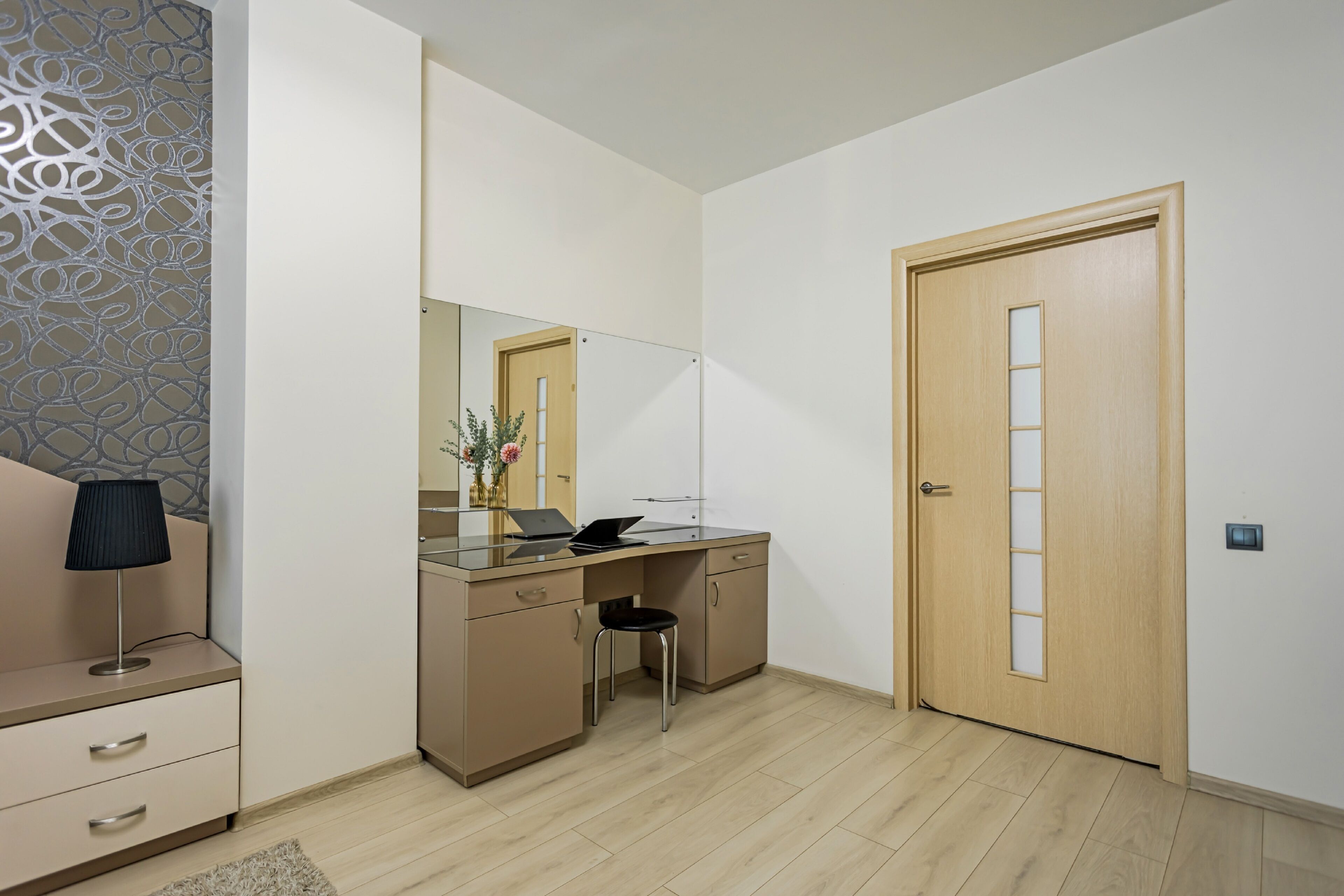 Une chambre à coucher moderne avec un lit, une table de chevet, une lampe et un grand miroir.