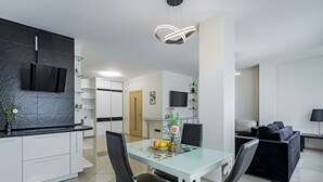 A modern kitchen with a black countertop, white cabinets, and a built-in microwave. There is a dining table with chairs and a vase with flowers. - Comfortable apartments  (Minsk)