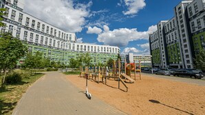 A playground area with sand and play equipment, surrounded by multi-story residential buildings. - Comfortable apartments  (Minsk)