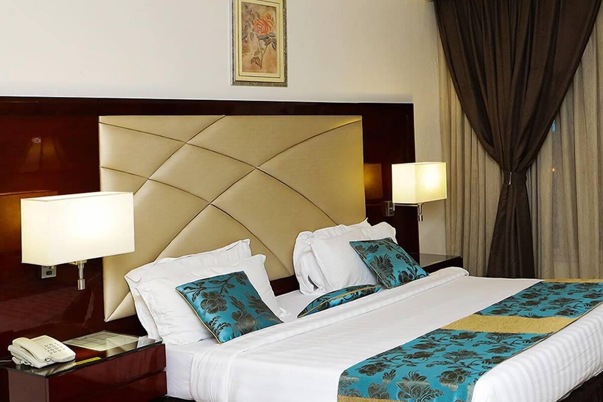 Een hotelkamer met een groot bed, twee bedlampen, een telefoon en een decoratief schilderij aan de muur.