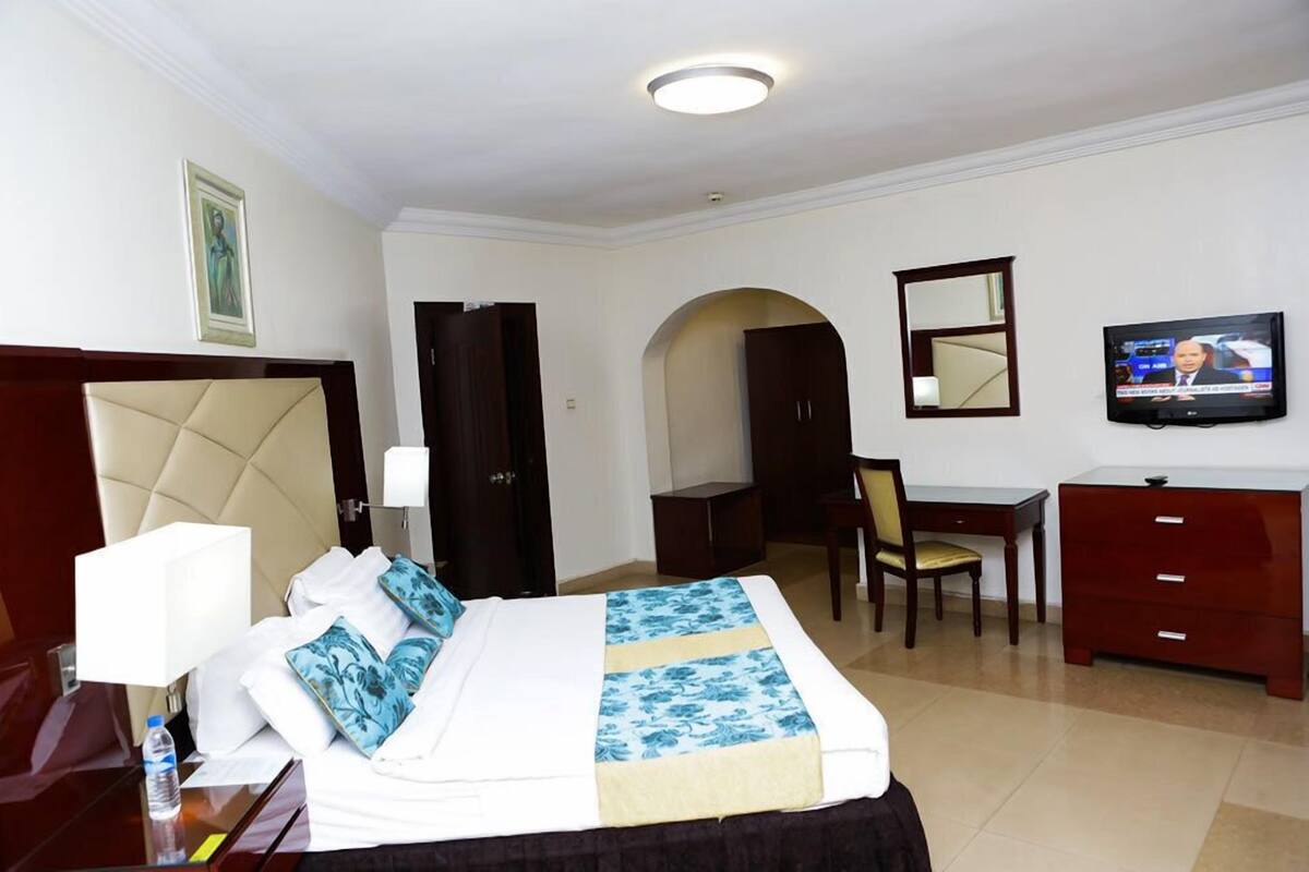 Een hotelkamer met een bed, een bureau, een stoel, een televisie en een garderobe.