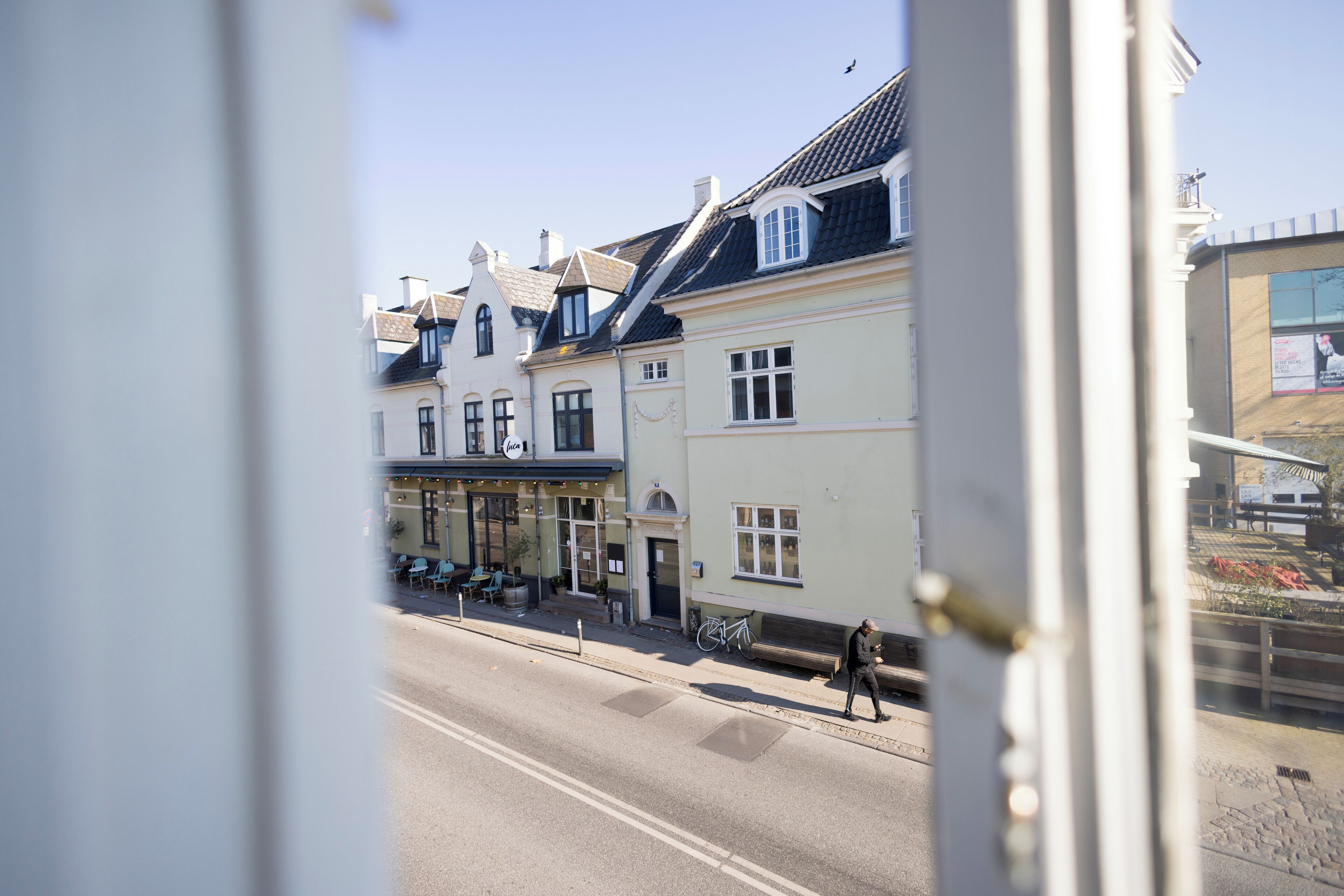 A street view of a building with a cafe and outdoor seating.