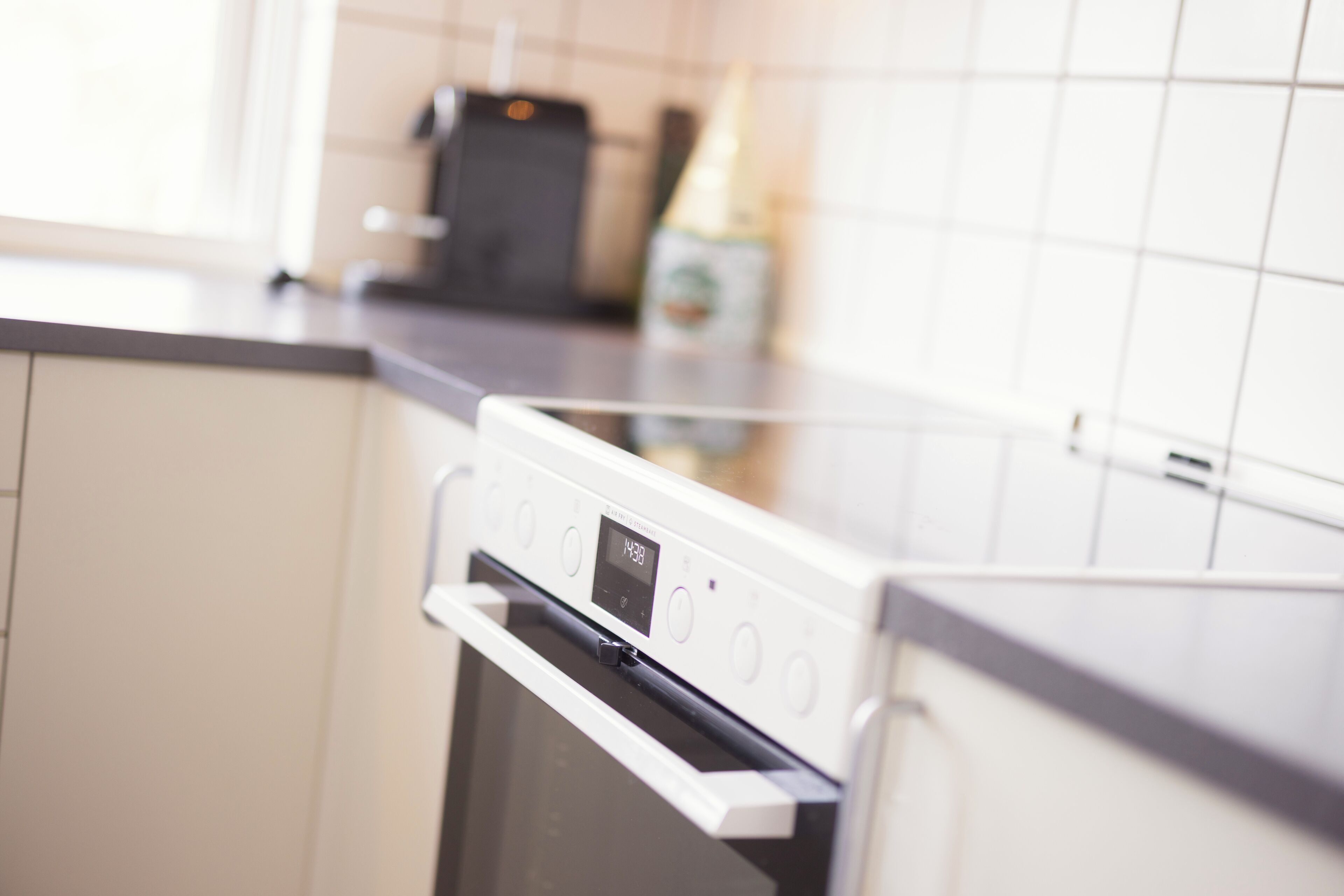 A modern kitchen with a built-in oven and a digital clock displaying the time.