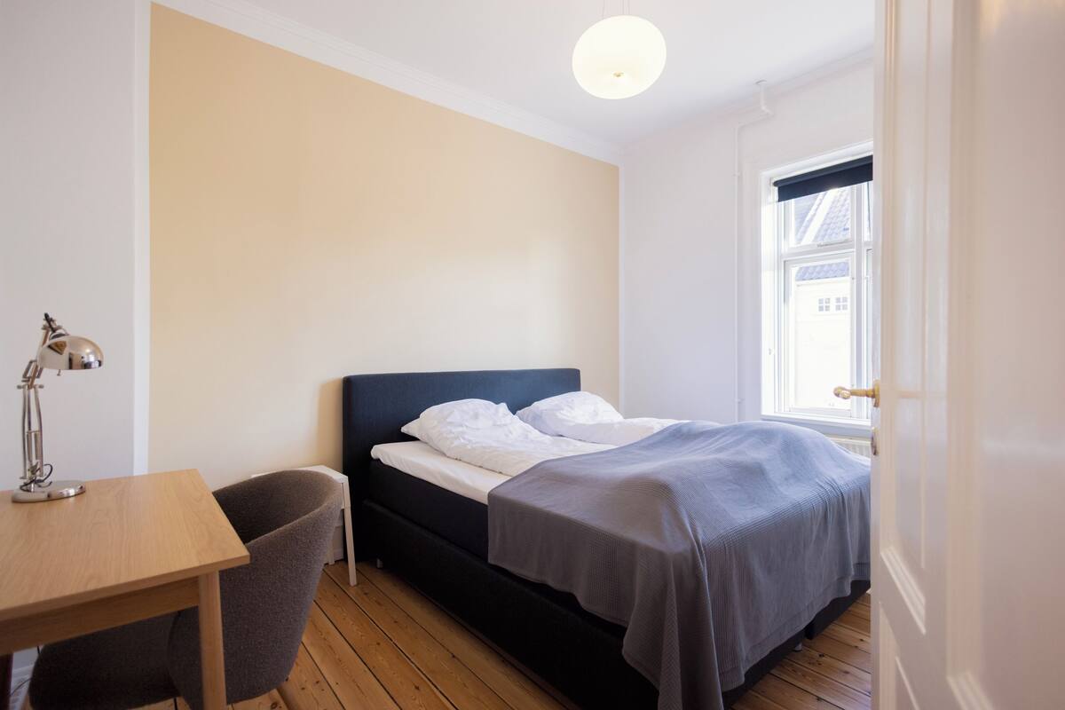 A bedroom with a bed, a desk, and a chair.