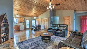 A spacious living room with a wooden ceiling, leather sofas, a coffee table, and a dining area with a table and chairs.
